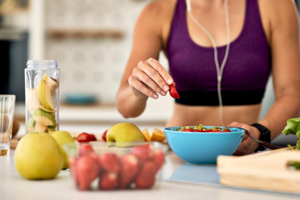 closeup-athletic-woman-adding-strawberries-while-making-fruit-salad-kitchen_637285-6186_jpg